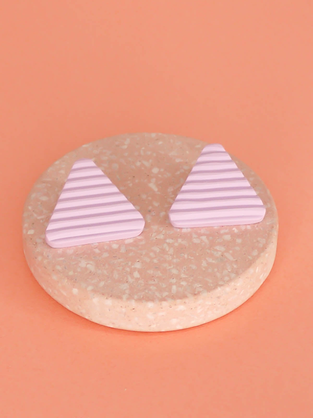 Lightweight lilac polymer clay triangle stud earrings in a fluted striped texture with stainless steel studs.