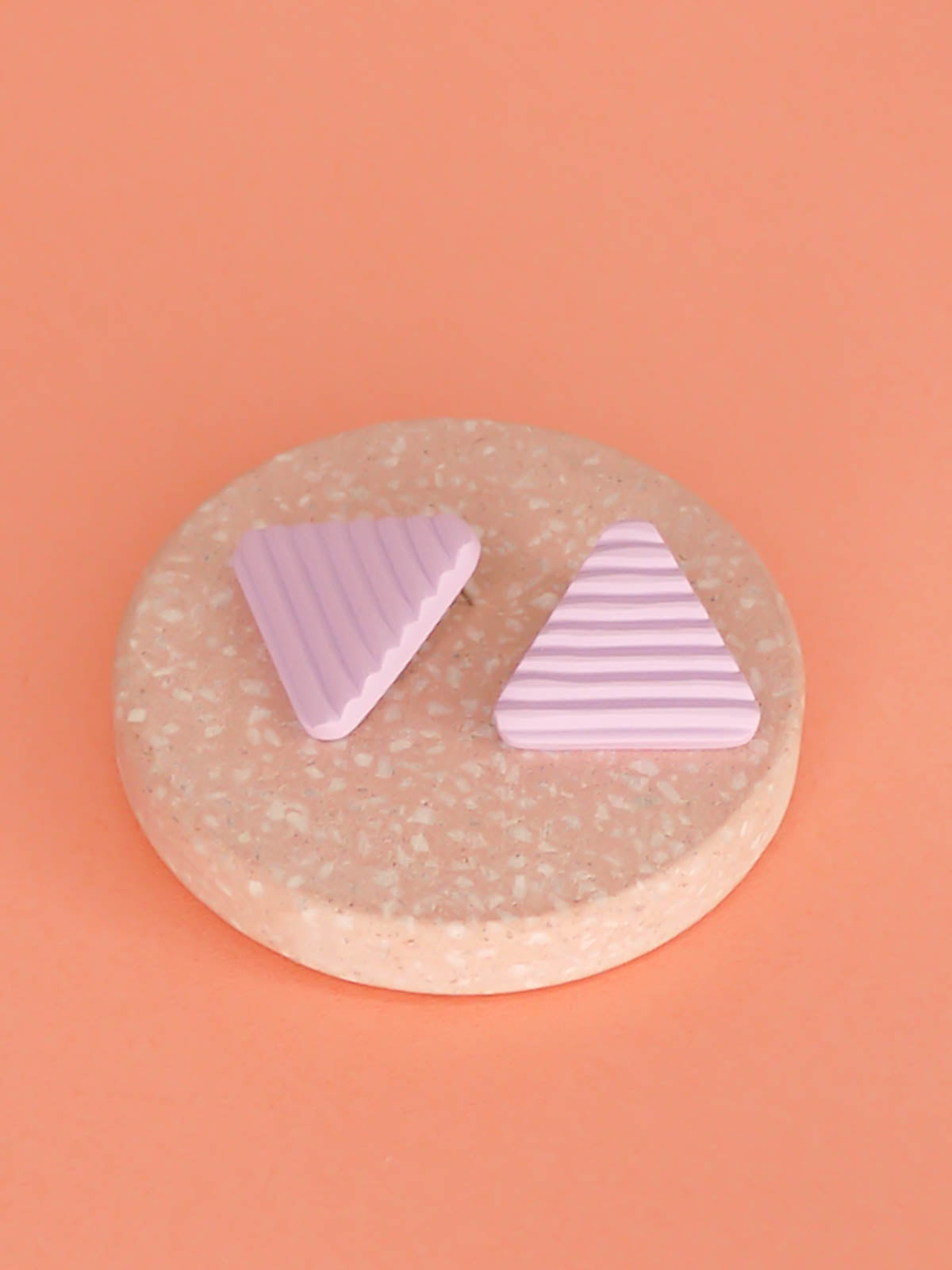 Lightweight lilac polymer clay triangle stud earrings in a fluted striped texture with stainless steel studs.