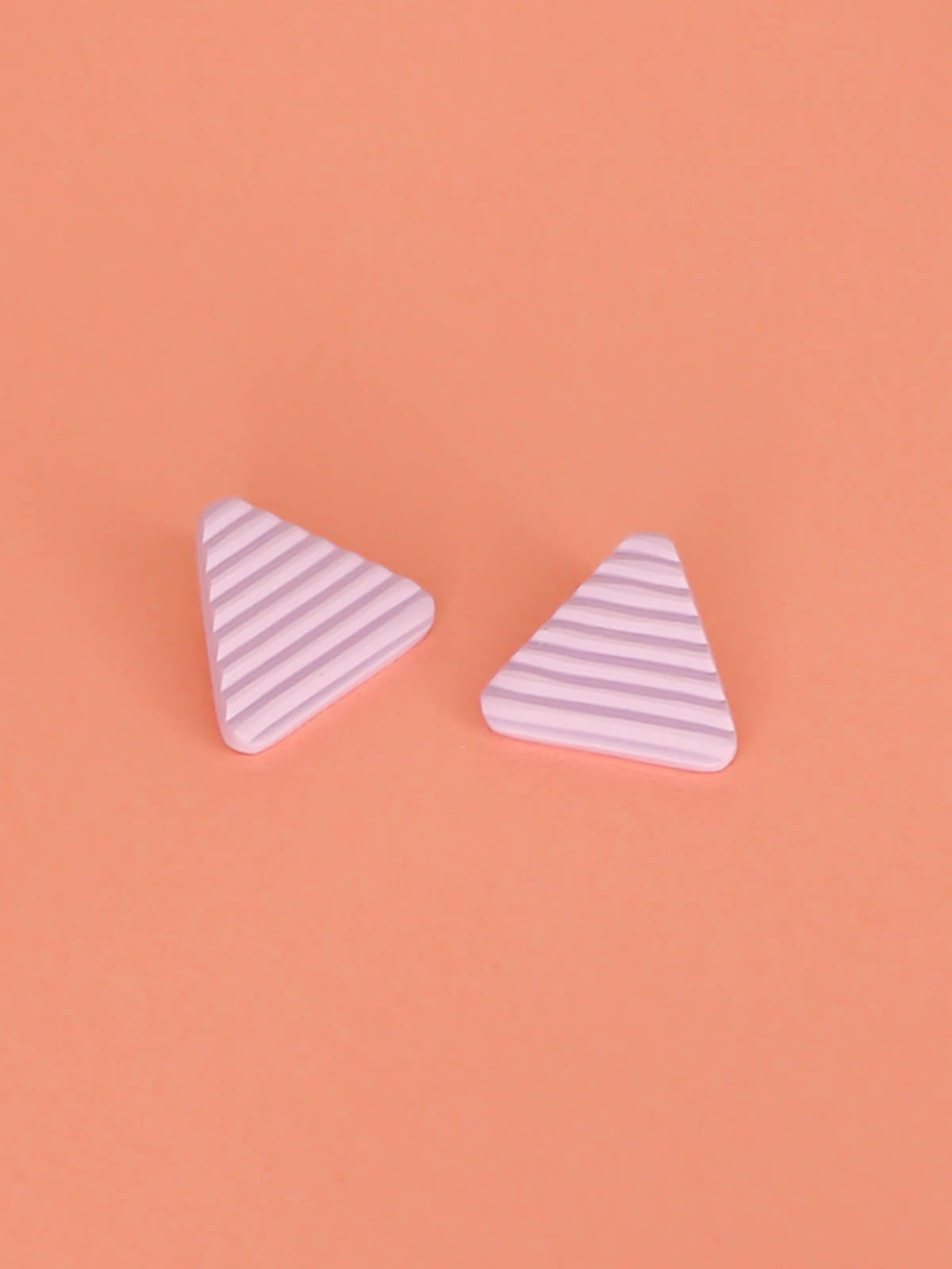 Lightweight lilac polymer clay triangle stud earrings in a fluted striped texture with stainless steel studs.