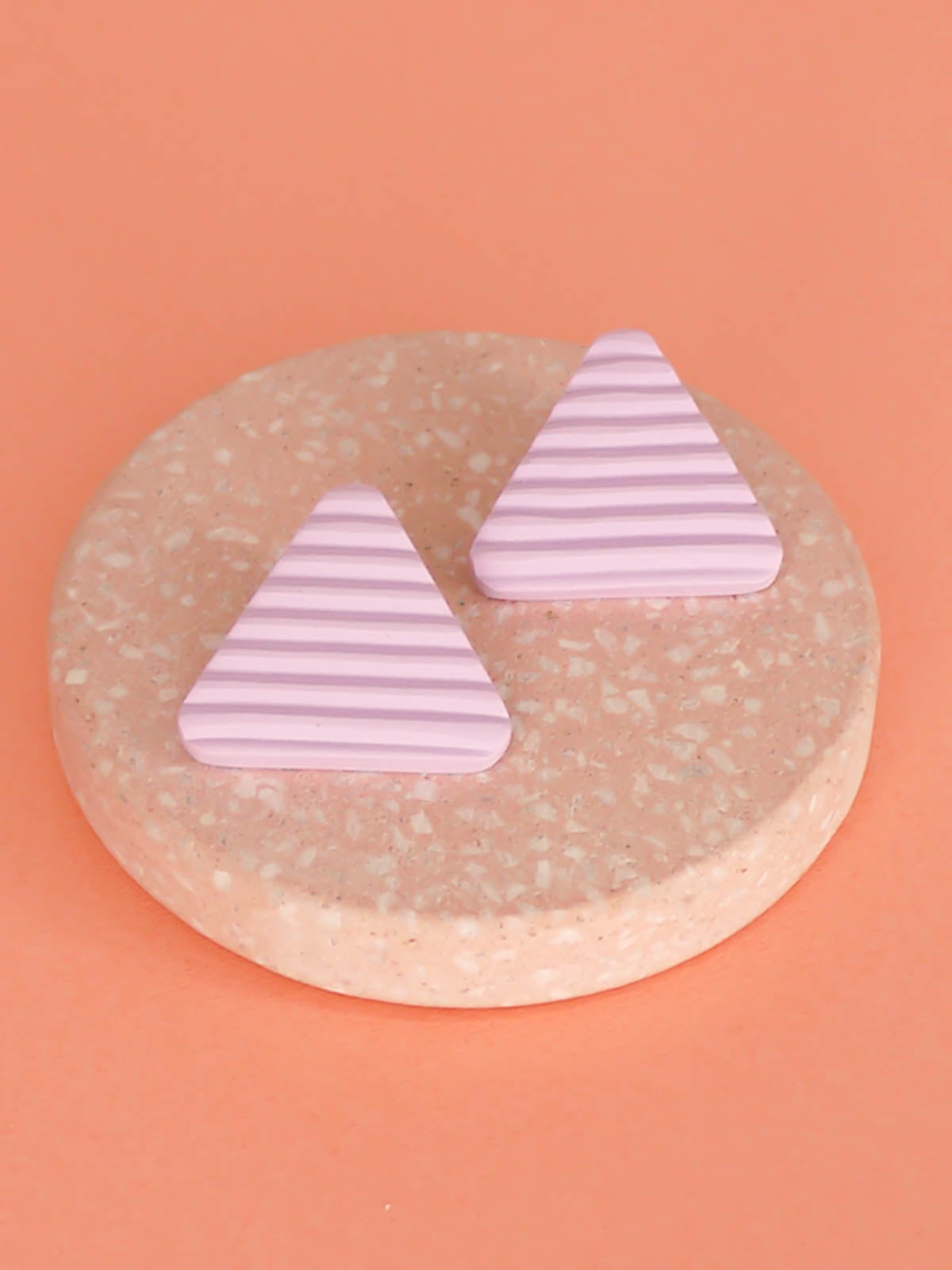 Lightweight lilac polymer clay triangle stud earrings in a fluted striped texture with stainless steel studs.