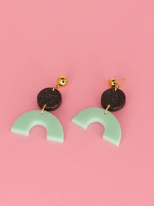 Geometric polymer clay dangle earrings earrings with a mint arch semi circle connected to a black glitter circle with gold plated brass circle studs.