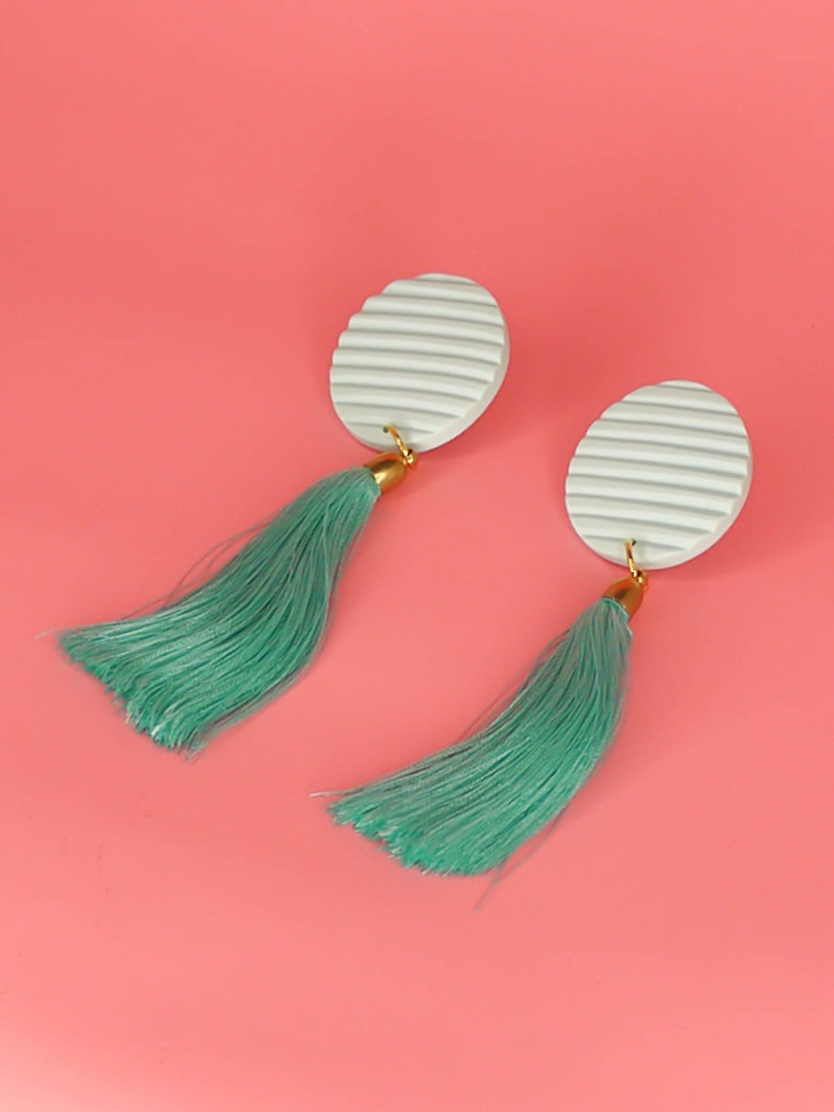 Long mint tassel dangle earrings with a fluted textured striped mint disk stud made out of polymer clay with a long mint silky tassel with a brass end cap and stainless steel posts