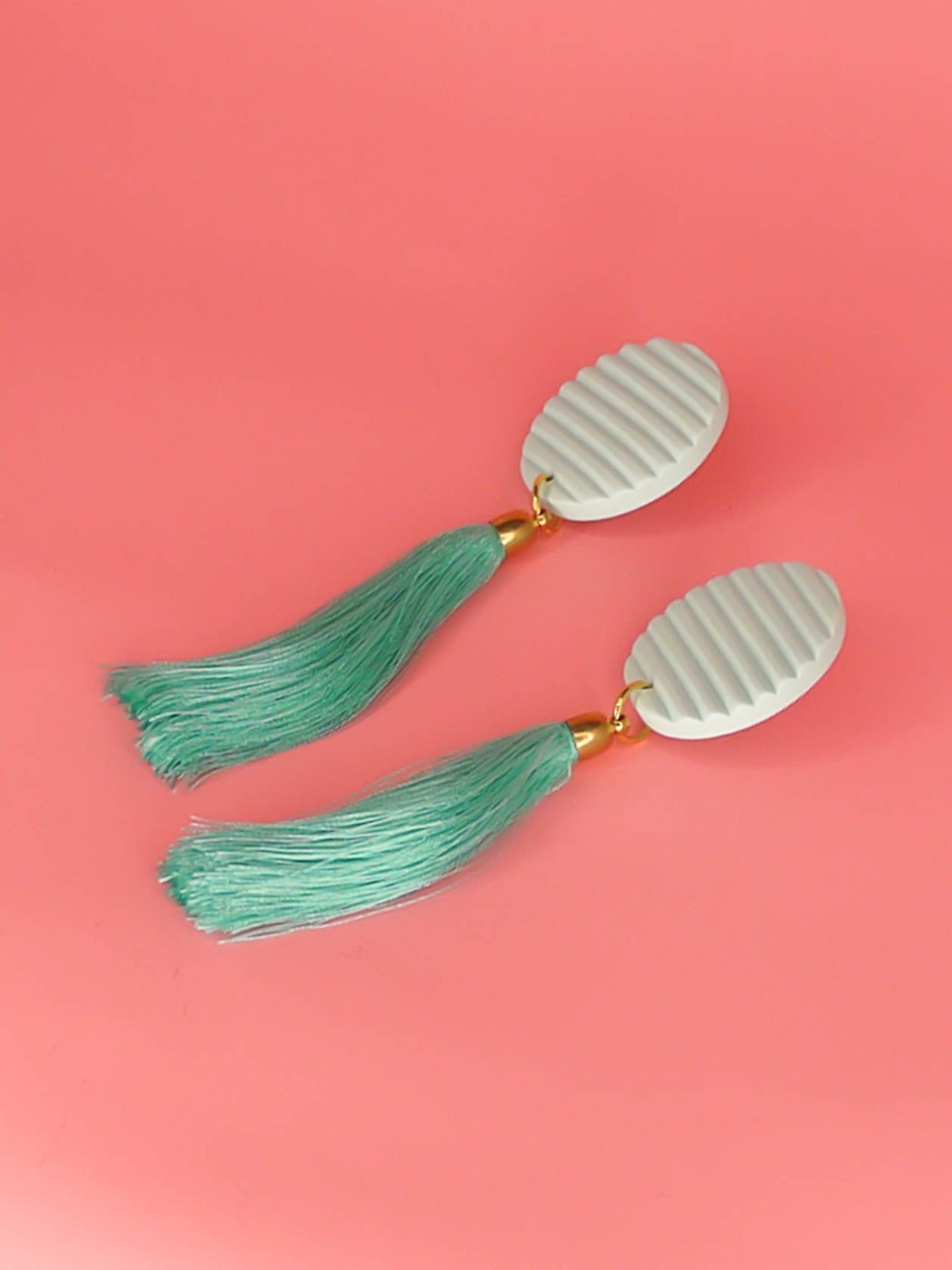 Long mint tassel dangle earrings with a fluted textured striped mint disk stud made out of polymer clay with a long mint silky tassel with a brass end cap and stainless steel posts