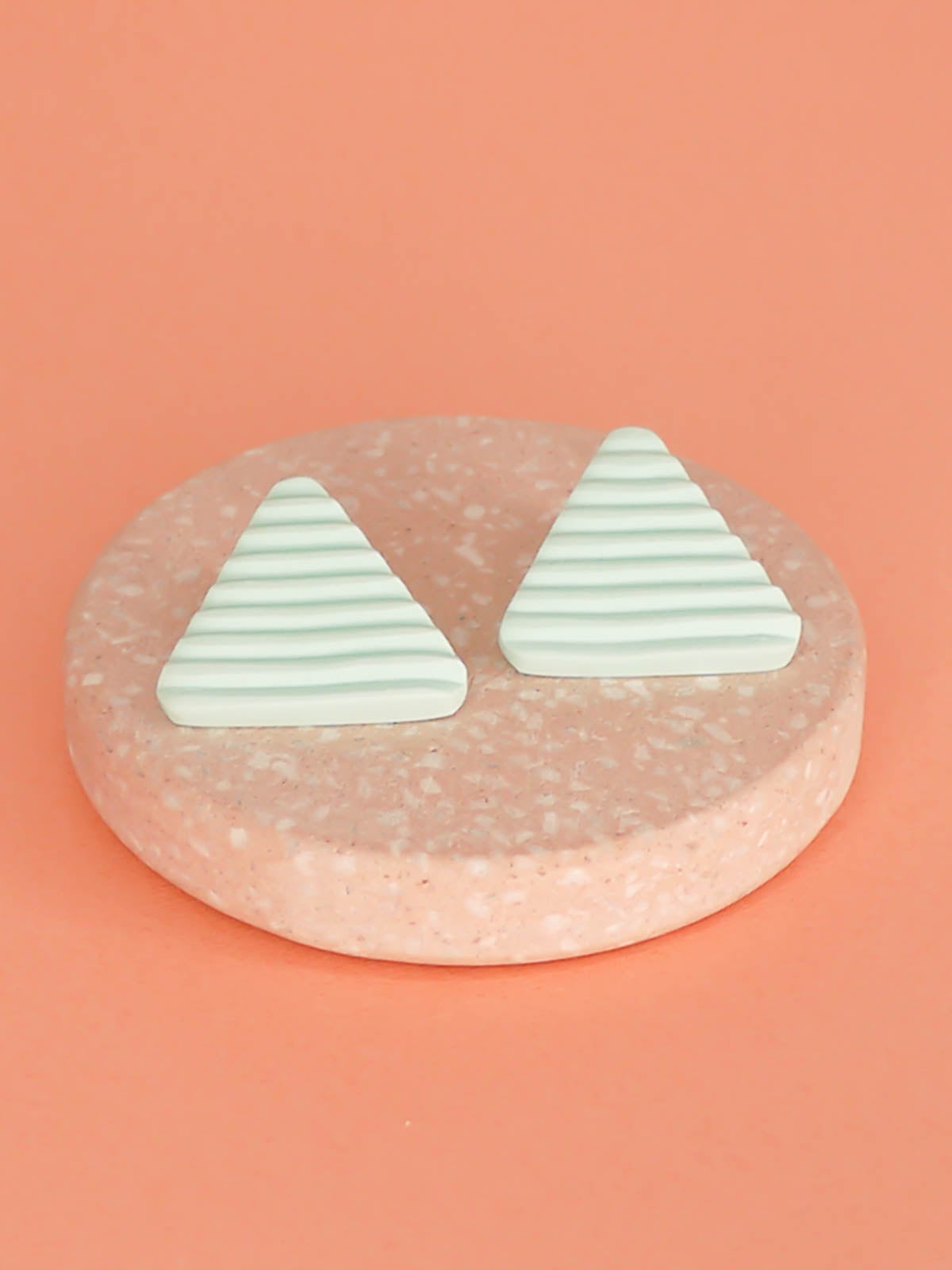 Lightweight mint polymer clay triangle stud earrings in a fluted striped texture with stainless steel studs.