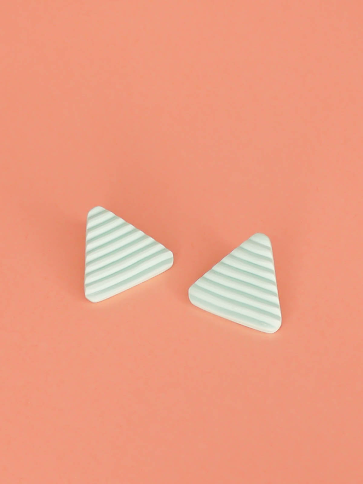 Lightweight mint polymer clay triangle stud earrings in a fluted striped texture with stainless steel studs.