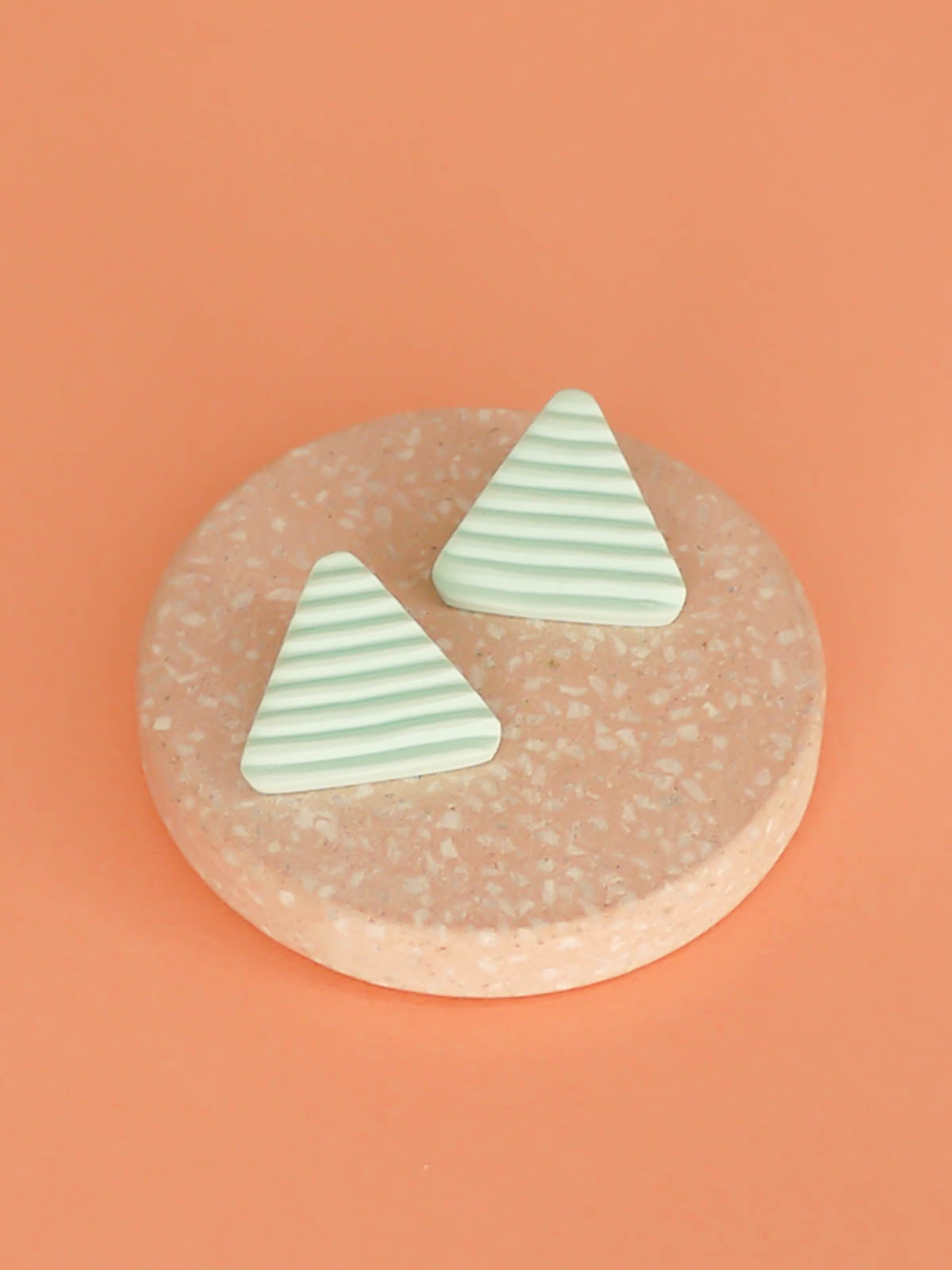 Lightweight mint polymer clay triangle stud earrings in a fluted striped texture with stainless steel studs.