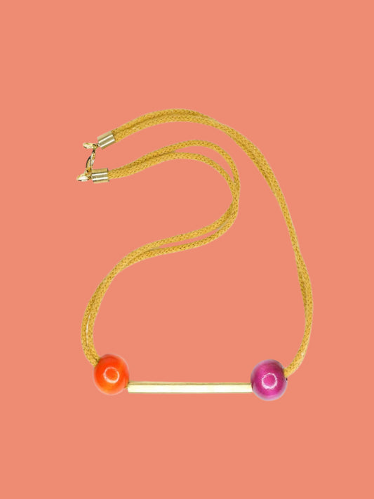 Mustard cotton rope bar necklace with a brass bar and contrasting wooden beads either side in orange and pink with a brass clasp