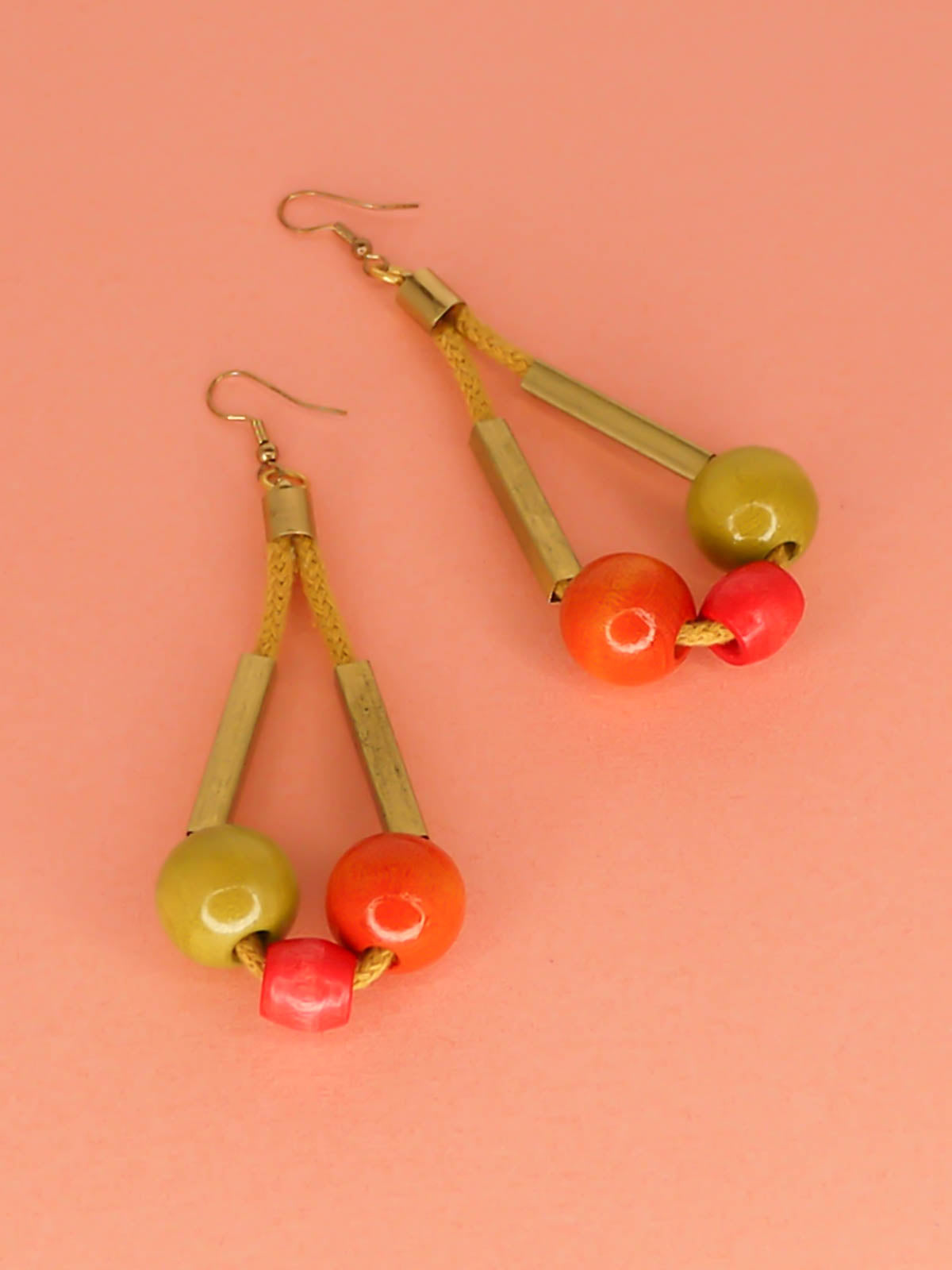 Long bead dangle statement earrings with wooden beads in watermelon, orange & green & brass tube beads strung on mustard coloured cotton rope with brass end caps, hung from gold plated brass earring hooks.