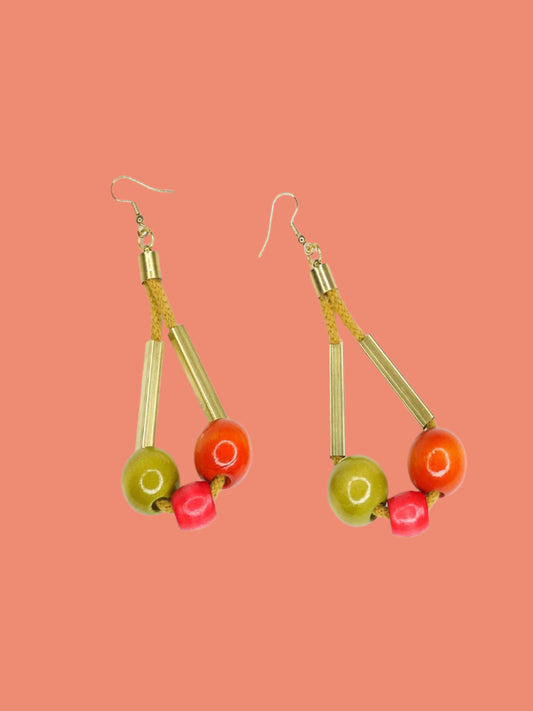 Long bead dangle statement earrings with wooden beads in watermelon, orange & green & brass tube beads strung on mustard coloured cotton rope with brass end caps, hung from gold plated brass earring hooks.