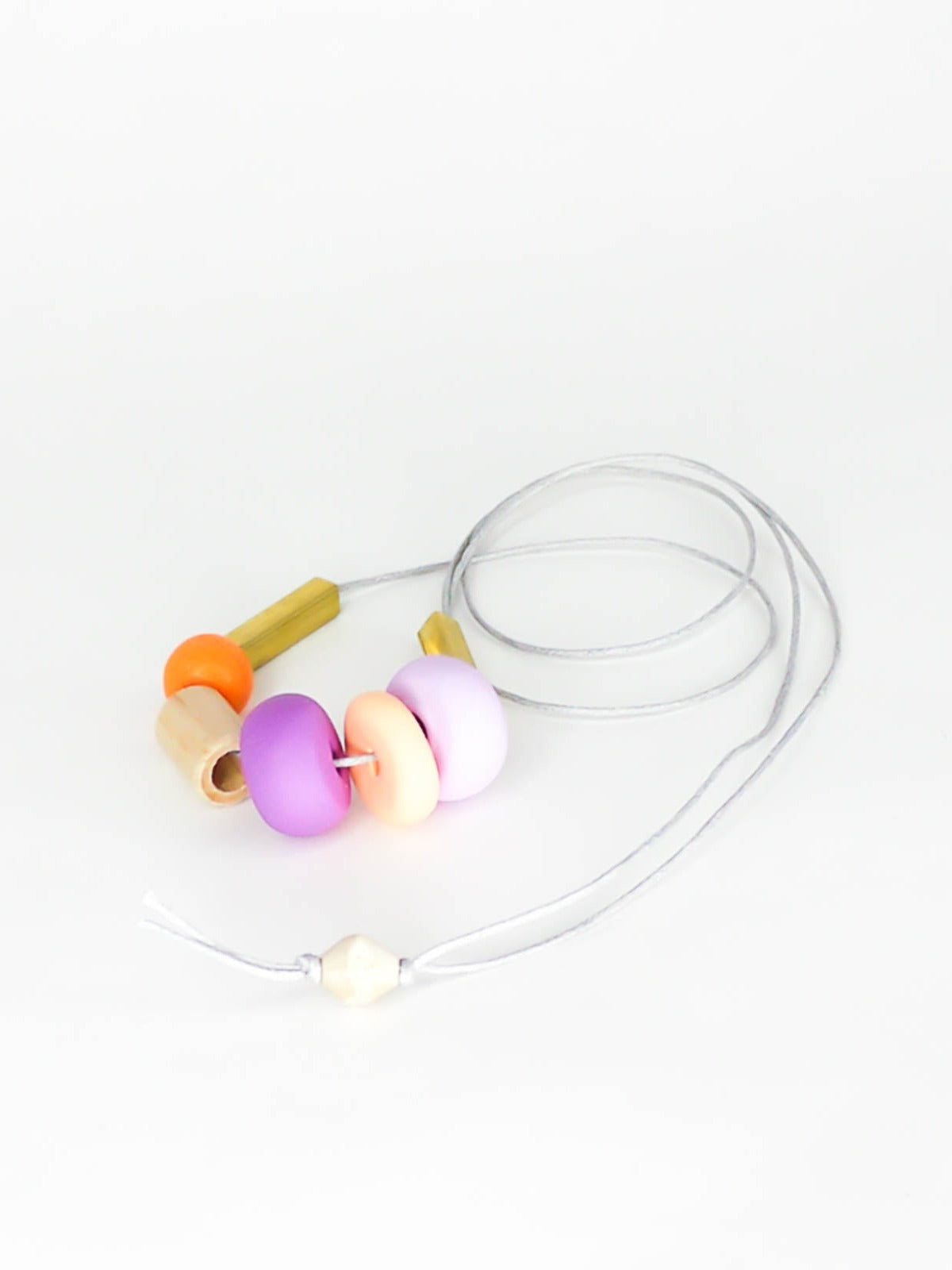 Lightweight geometric colourful bead necklace with 3 handmade polymer clay beads in peach, lilac & purple- wood tube bead & orange wood bead, brass tube beads on either side, strung on a cotton cord with a wood bead knotted at the end  