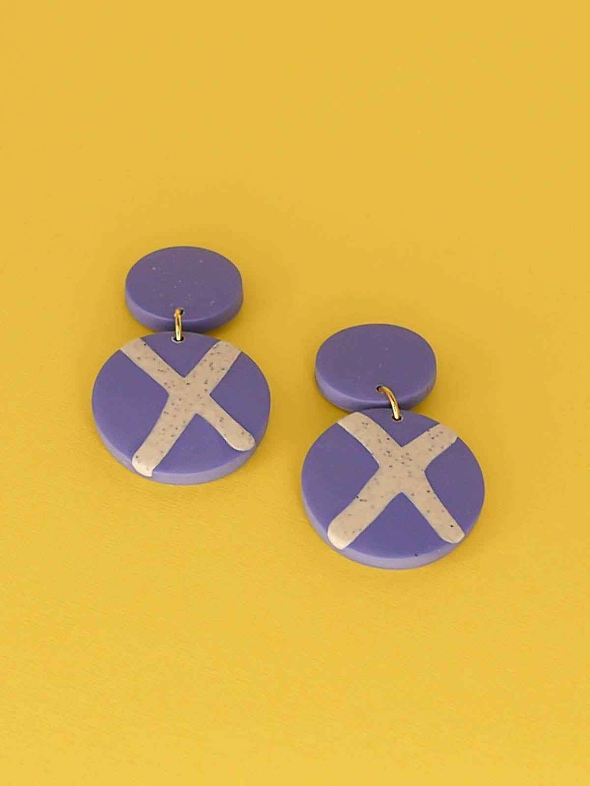 Polymer clay dangle statement earrings with a periwinkle blue stud connected to a periwinkle blue circle with a granite cross in the centre