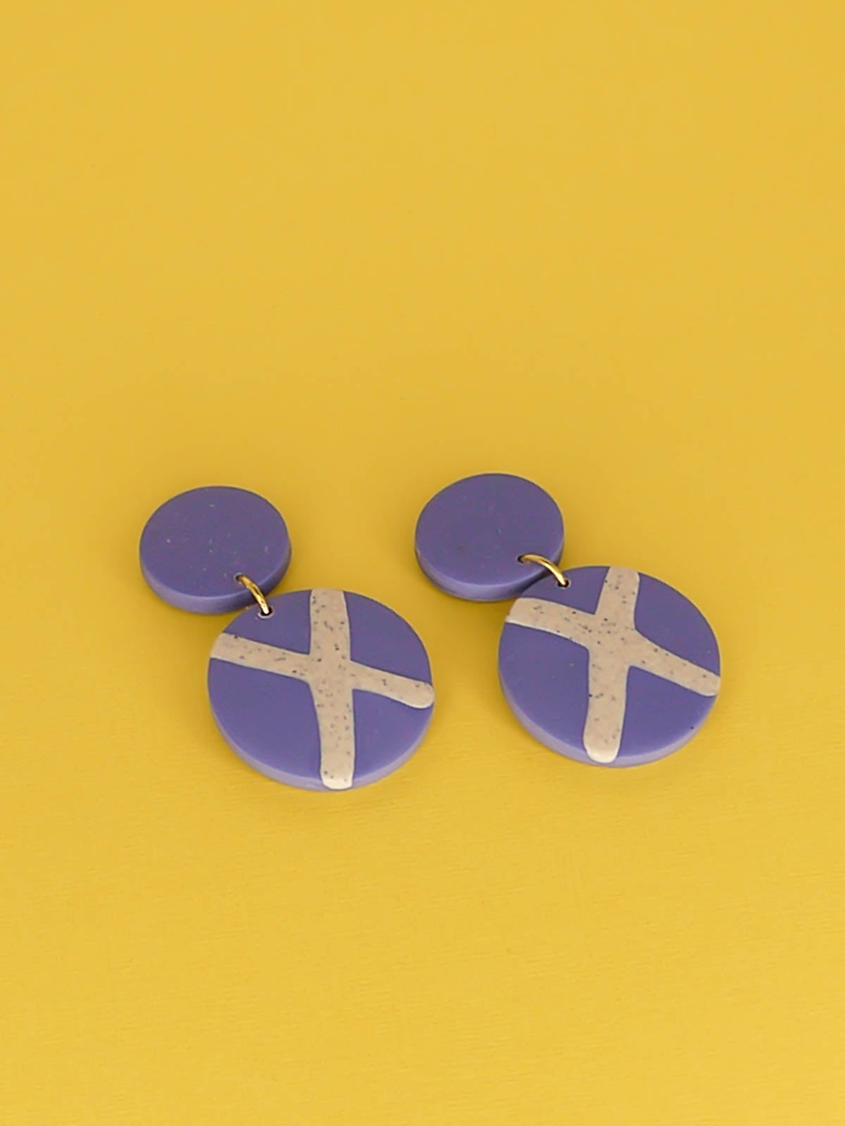 Polymer clay dangle statement earrings with a periwinkle blue stud connected to a periwinkle blue circle with a granite cross in the centre