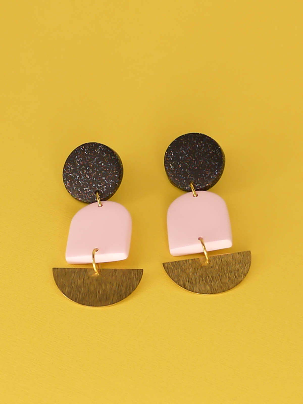 Geometric lightweight arch statement earrings with a black glitter polymer clay stud, a pale pink polymer arch and a textured brass semi circle