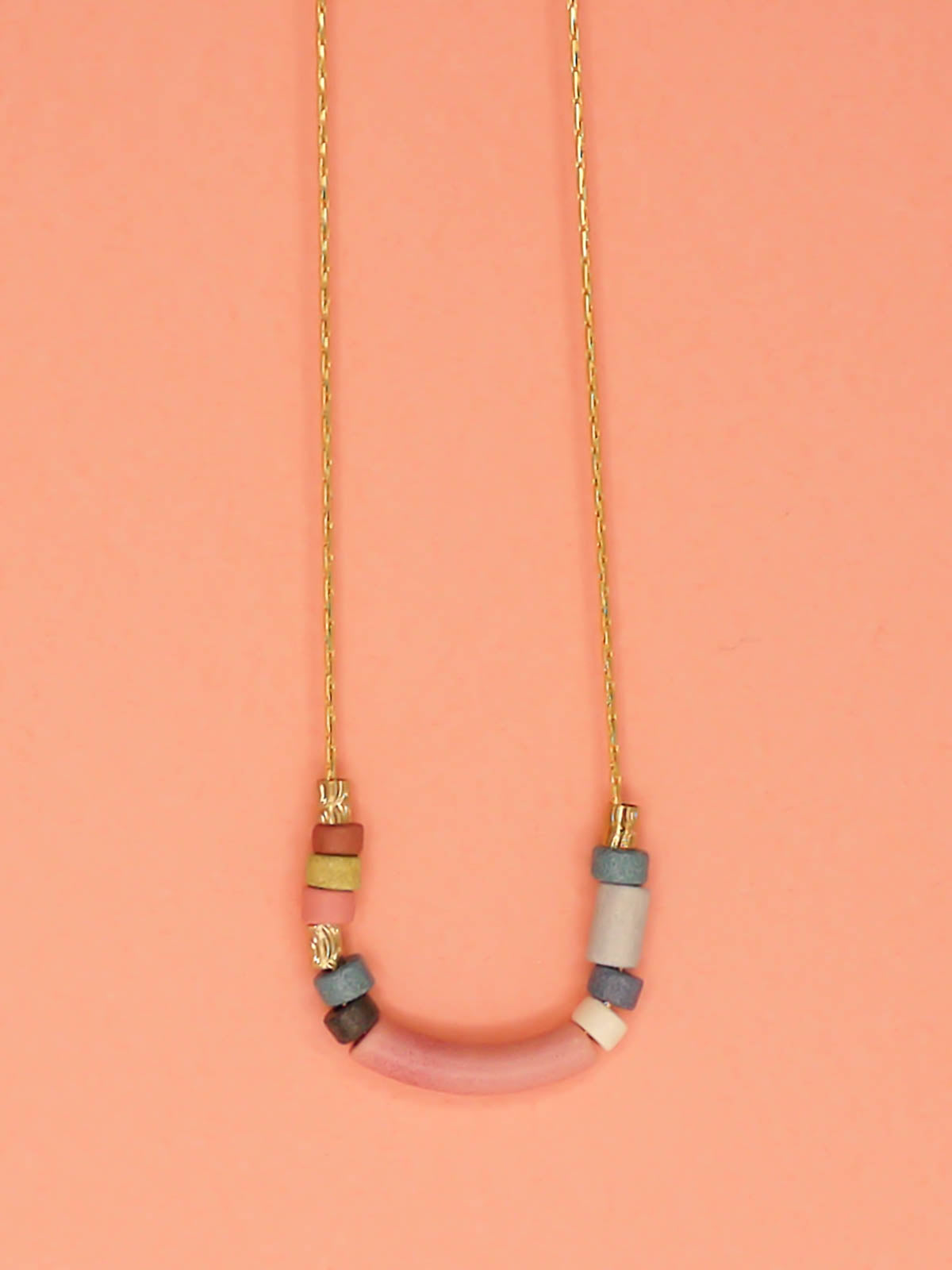 Pink curved bar ceramic bead necklace with colourful ceramic tube and brass beads strung on a gold plated thin chain with clasp