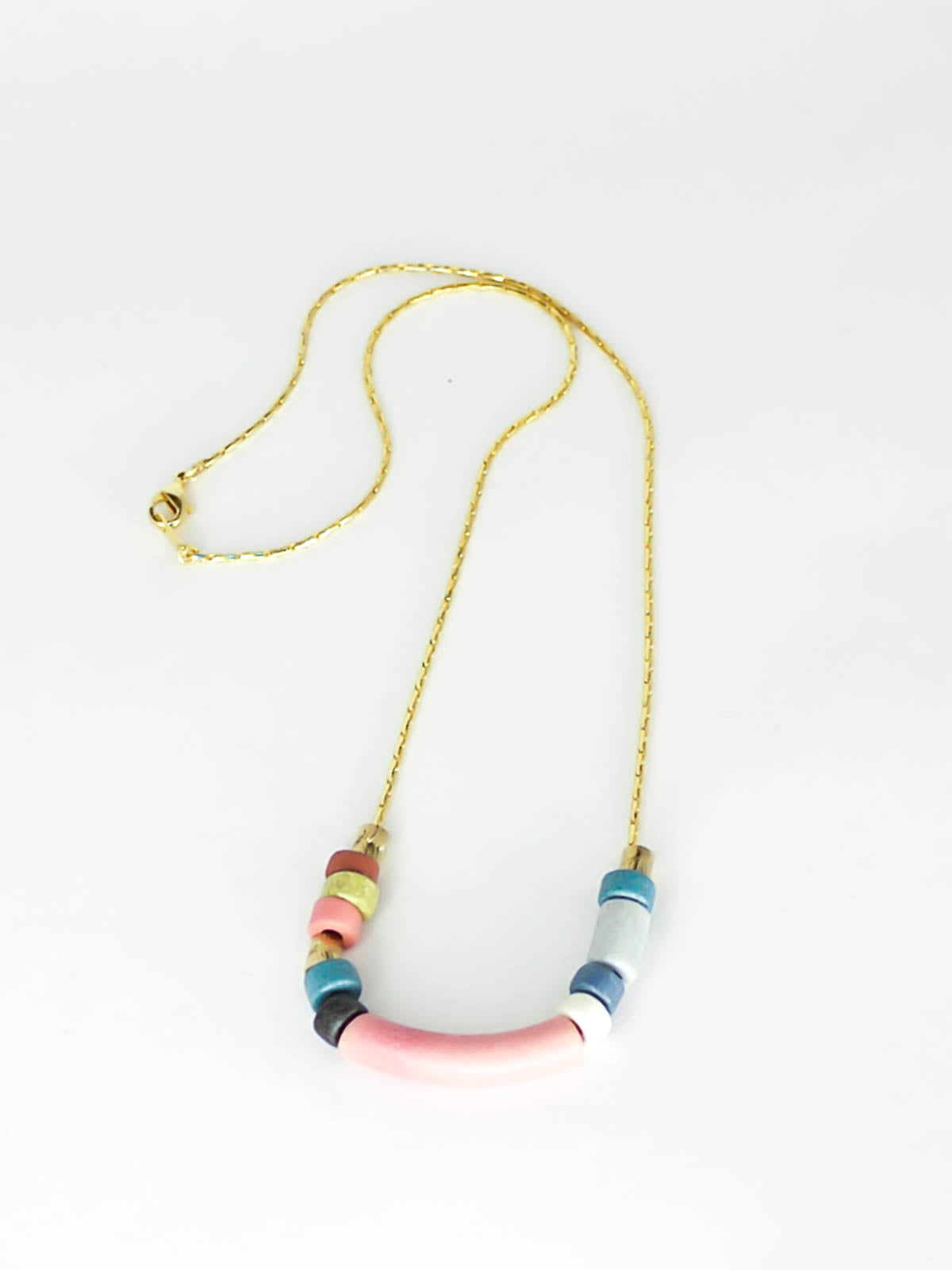 Pink curved bar ceramic bead necklace with colourful ceramic tube and brass beads strung on a gold plated thin chain with clasp