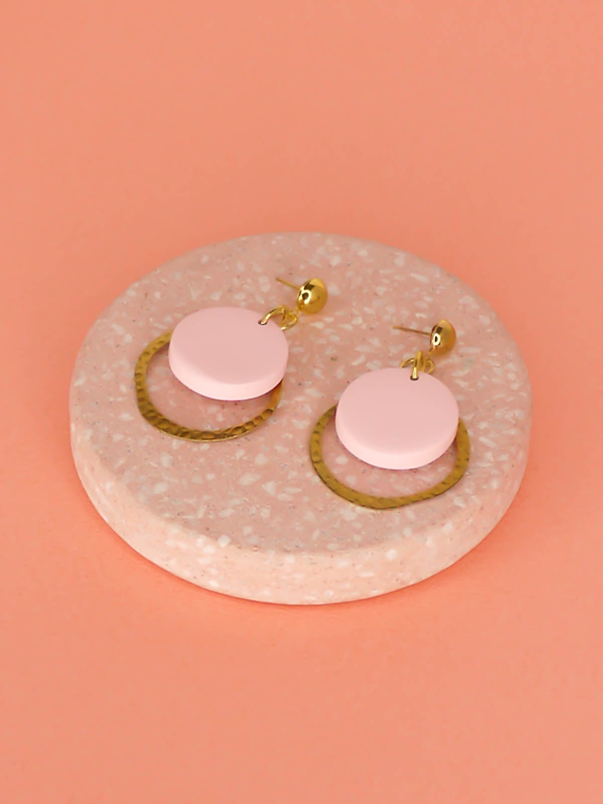 Geometric modern hoop dangle earrings with a textured brass hoop and a pastel pink polymer clay disk with gold plated brass studs