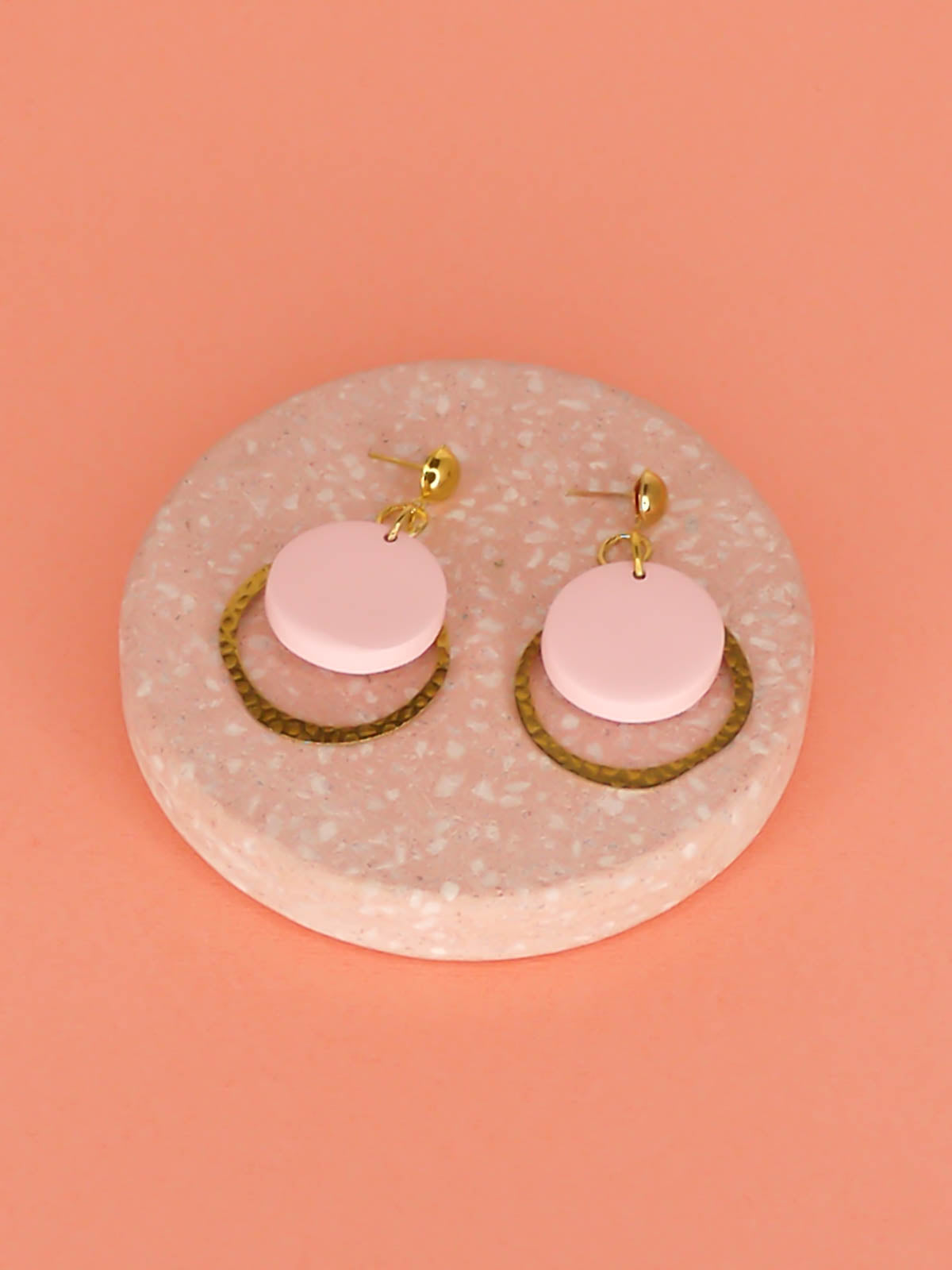 Geometric modern hoop dangle earrings with a textured brass hoop and a pastel pink polymer clay disk with gold plated brass studs