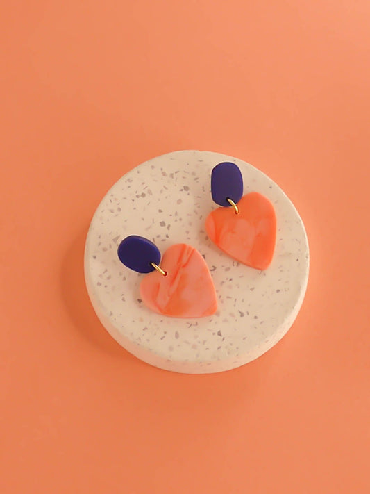 Pink marble heart earrings with a cobalt blue rectangular stud with stainless steel posts made out of polymer clay