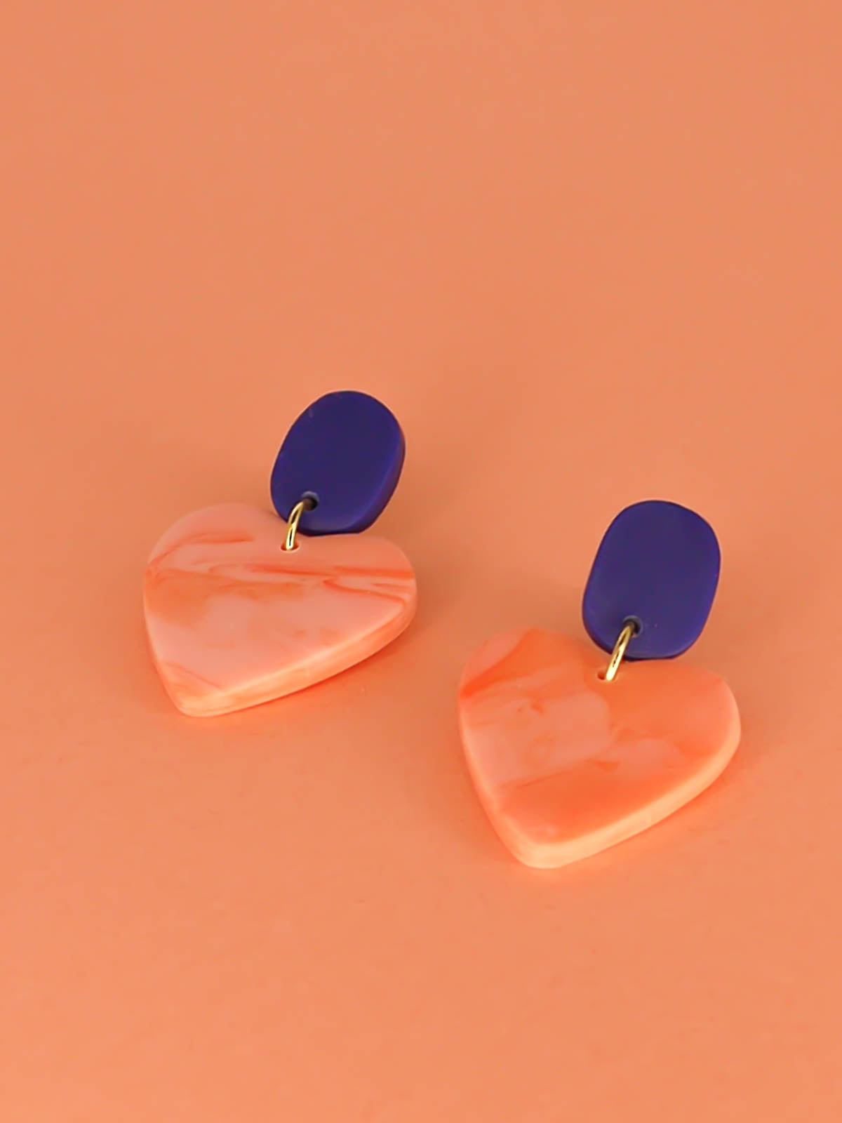 Pink marble heart earrings with a cobalt blue rectangular stud with stainless steel posts made out of polymer clay