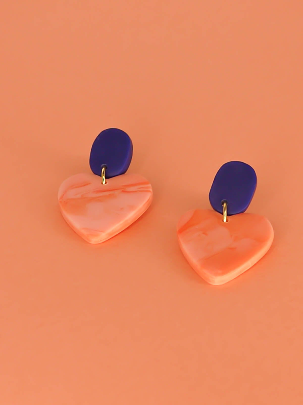 Pink marble heart earrings with a cobalt blue rectangular stud with stainless steel posts made out of polymer clay