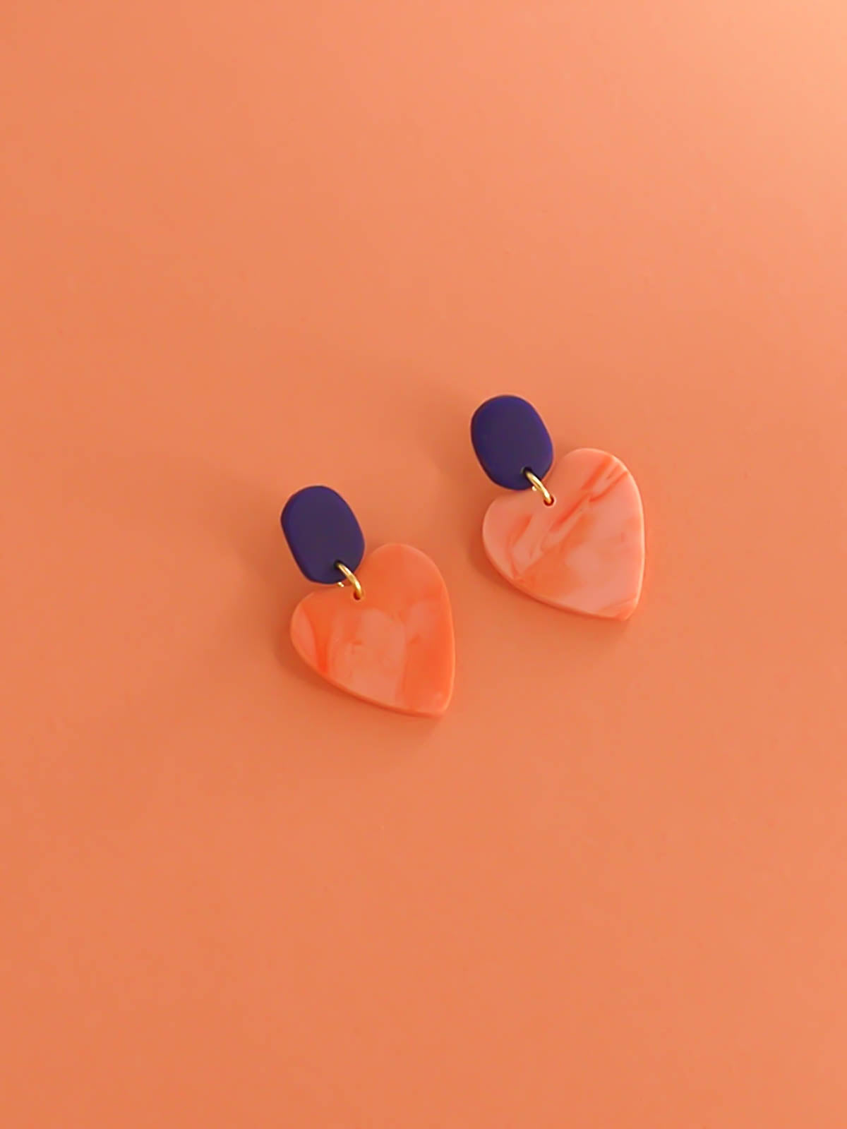 Pink marble heart earrings with a cobalt blue rectangular stud with stainless steel posts made out of polymer clay