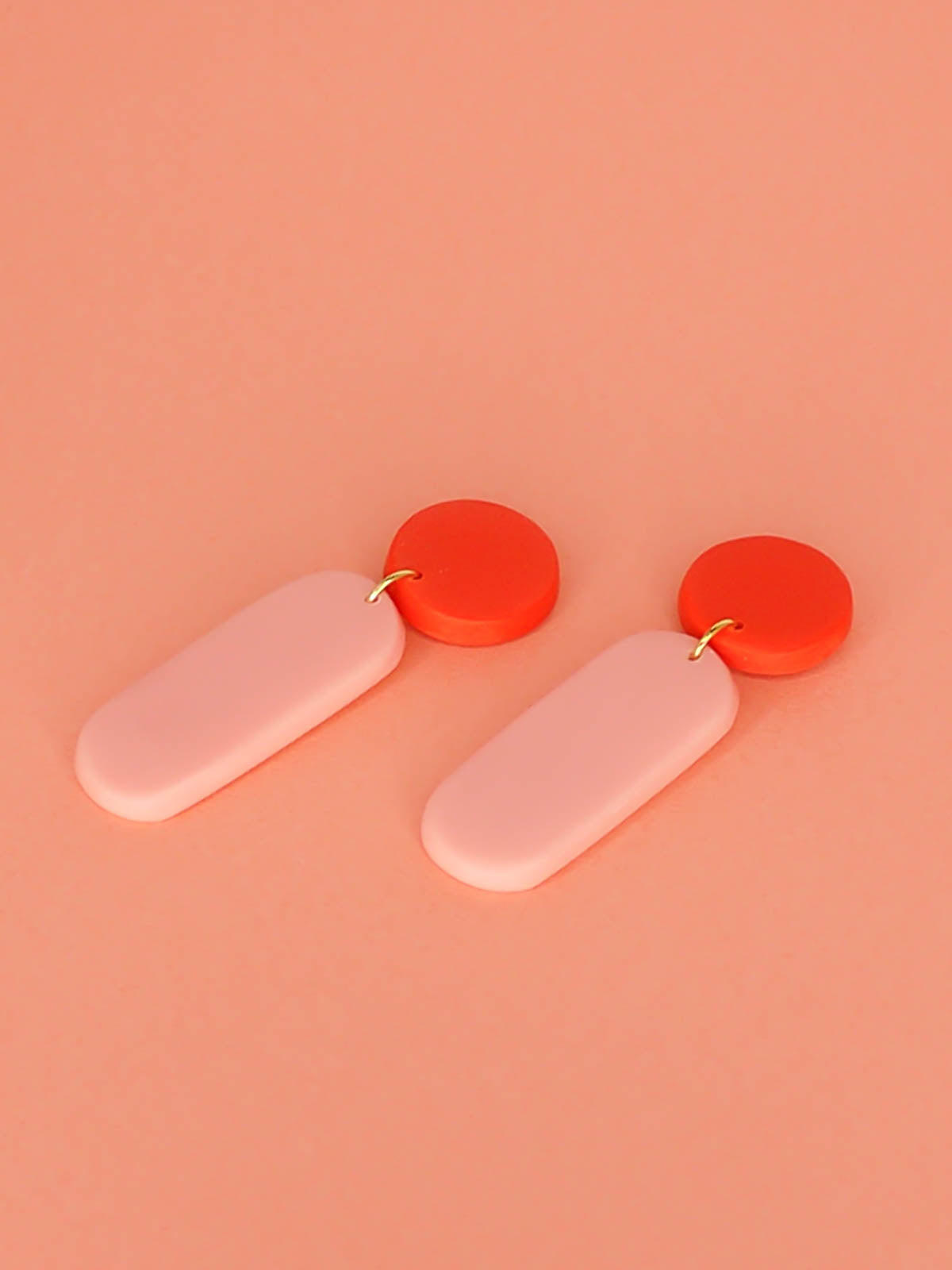 Statement dangle earrings with a rectangle pink stick dangle and red stud, with stainless steel posts, made out of lightweight polymer clay