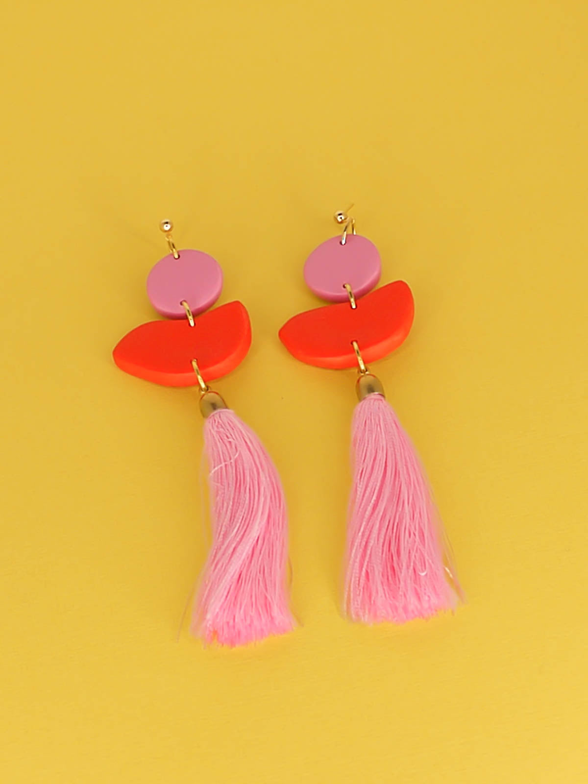 Statement dangle earrings with 24k gold plated ball studs connected to a pink polymer clay circle & a red polymer clay semi circle with a pale pink long tassel