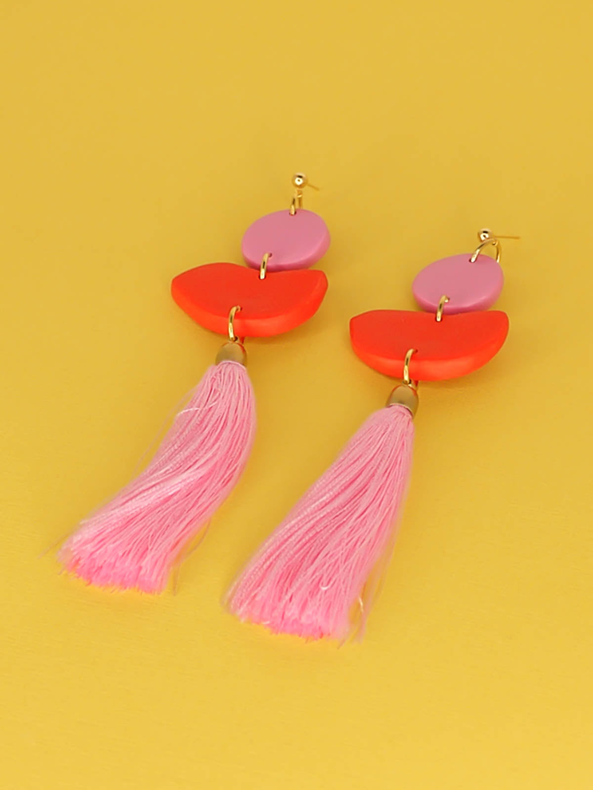 Statement dangle earrings with 24k gold plated ball studs connected to a pink polymer clay circle & a red polymer clay semi circle with a pale pink long tassel