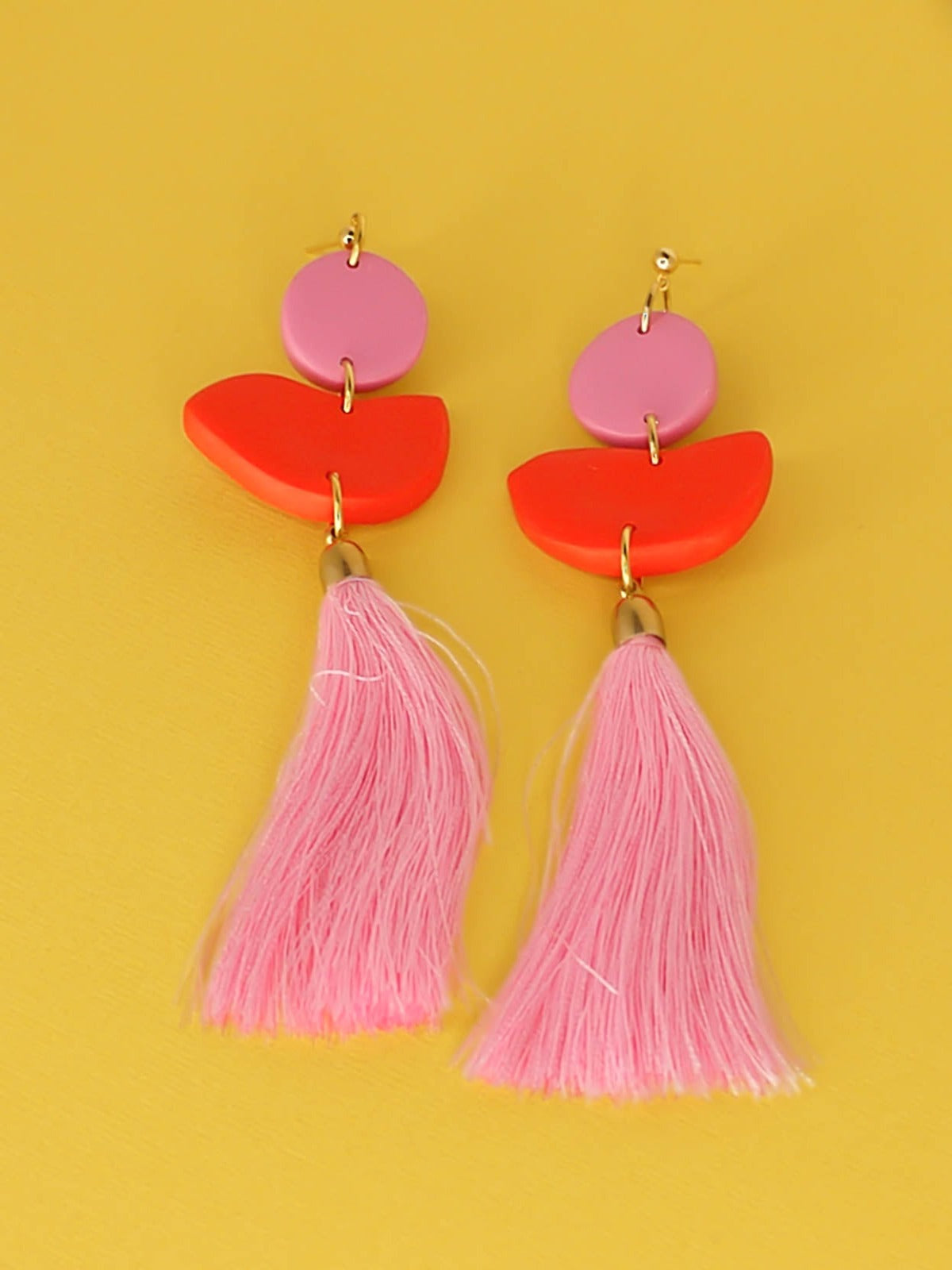 Statement dangle earrings with 24k gold plated ball studs connected to a pink polymer clay circle & a red polymer clay semi circle with a pale pink long tassel