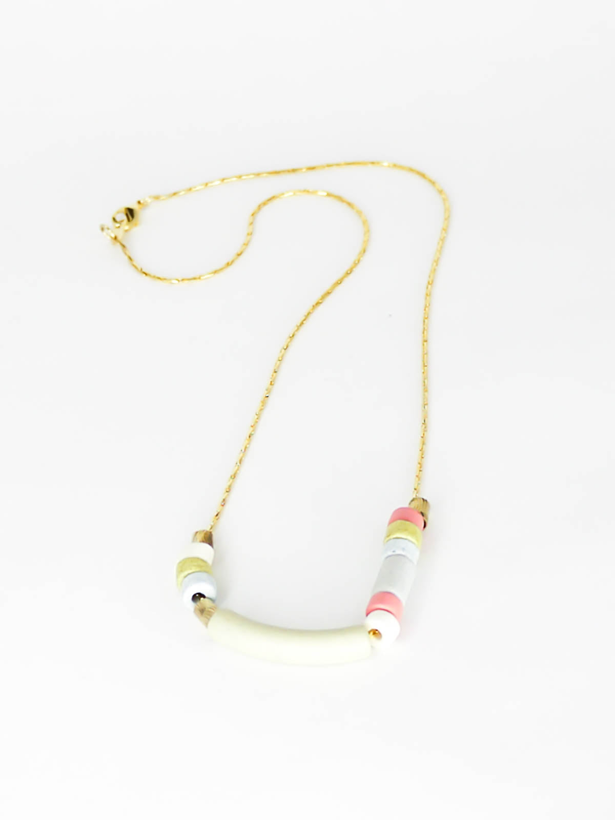 Delicate ceramic beaded necklace with a curved bar pistachio bead and multicoloured tube and brass beads strung on a gold plated snake chain