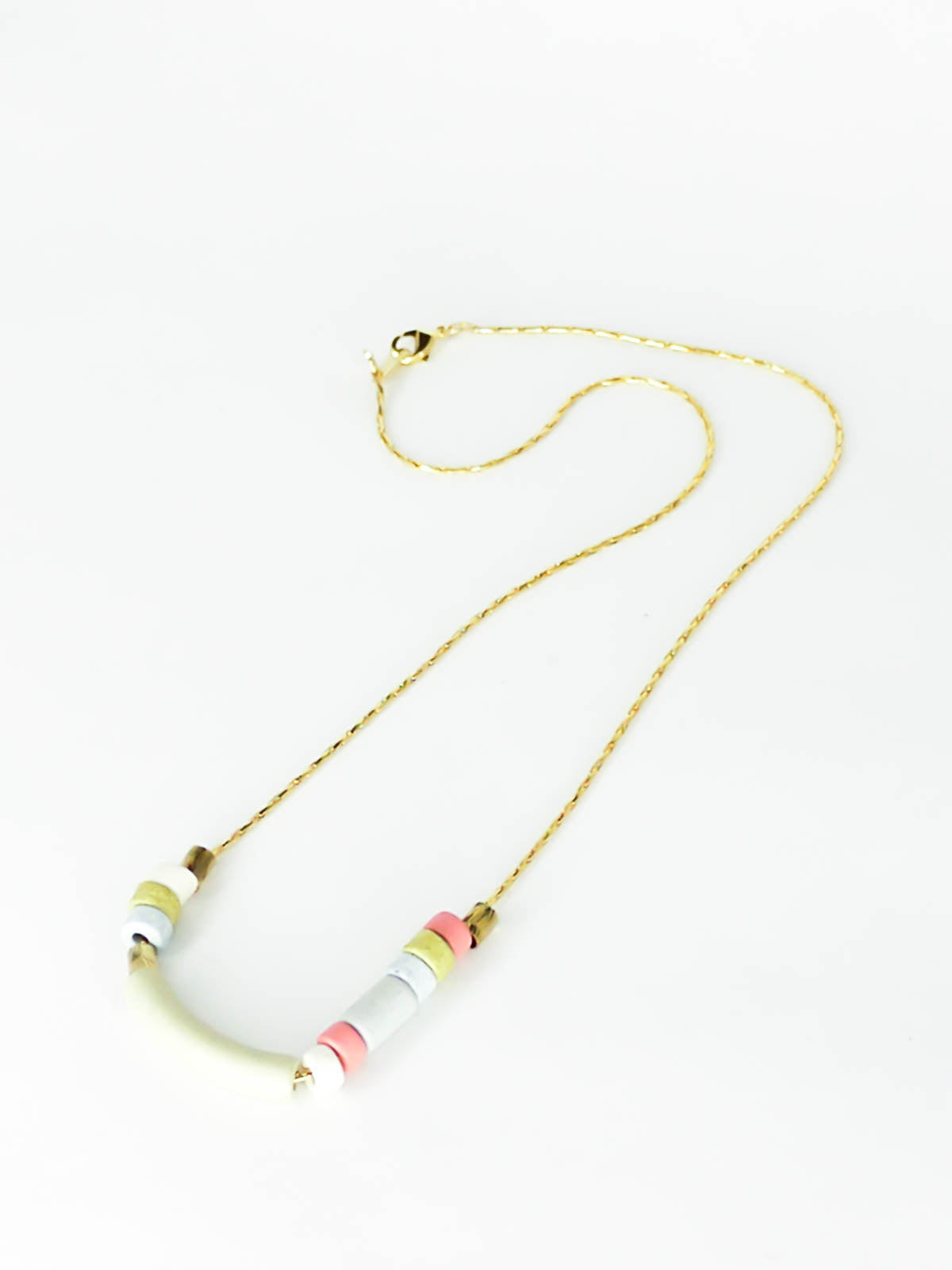 Delicate ceramic beaded necklace with a curved bar pistachio bead and multicoloured tube and brass beads strung on a gold plated snake chain