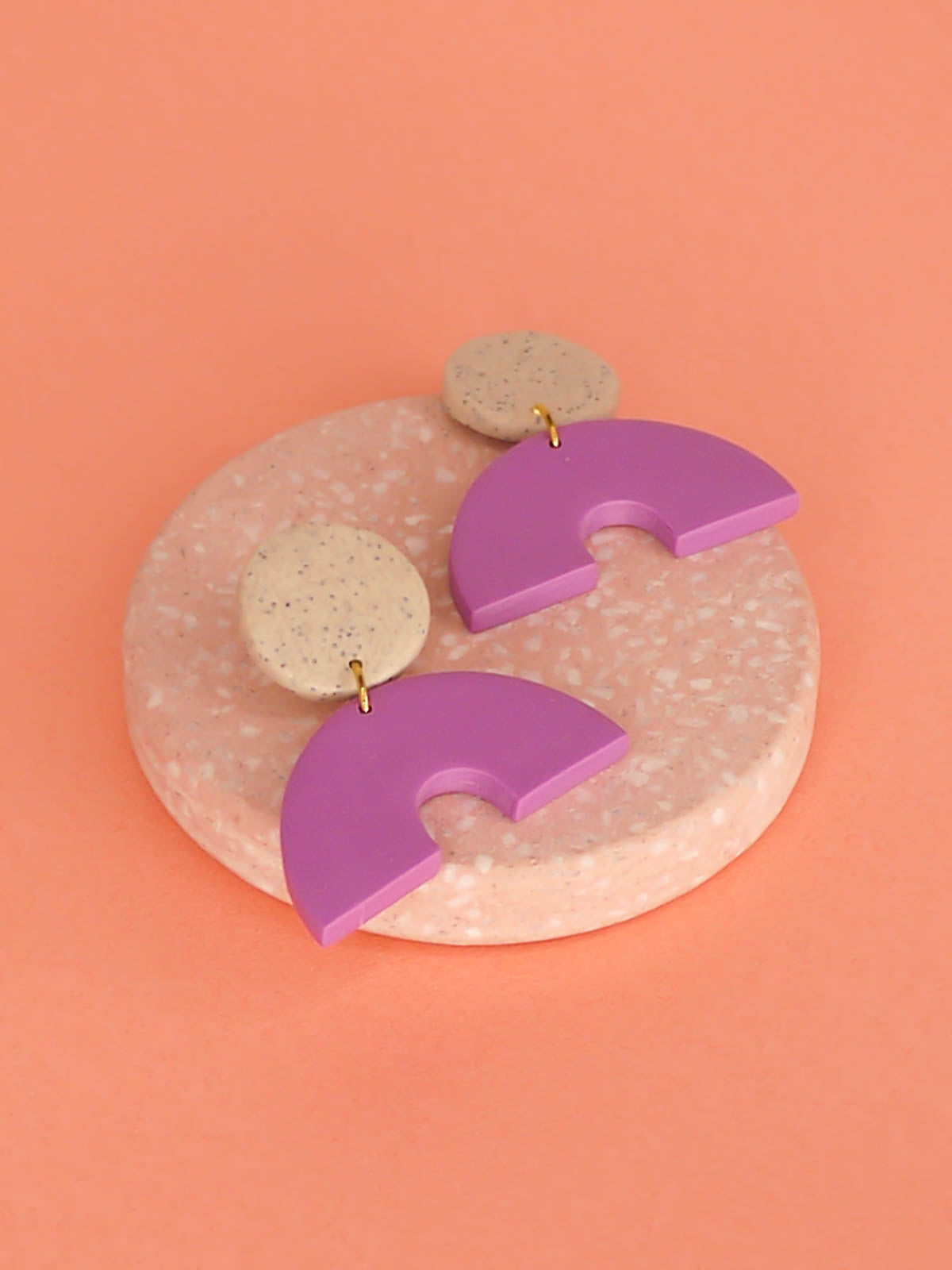 Geometric arch dangle earrings with a purple arch connected to a granite stud with stainless steel posts, made out of lightweight polymer clay