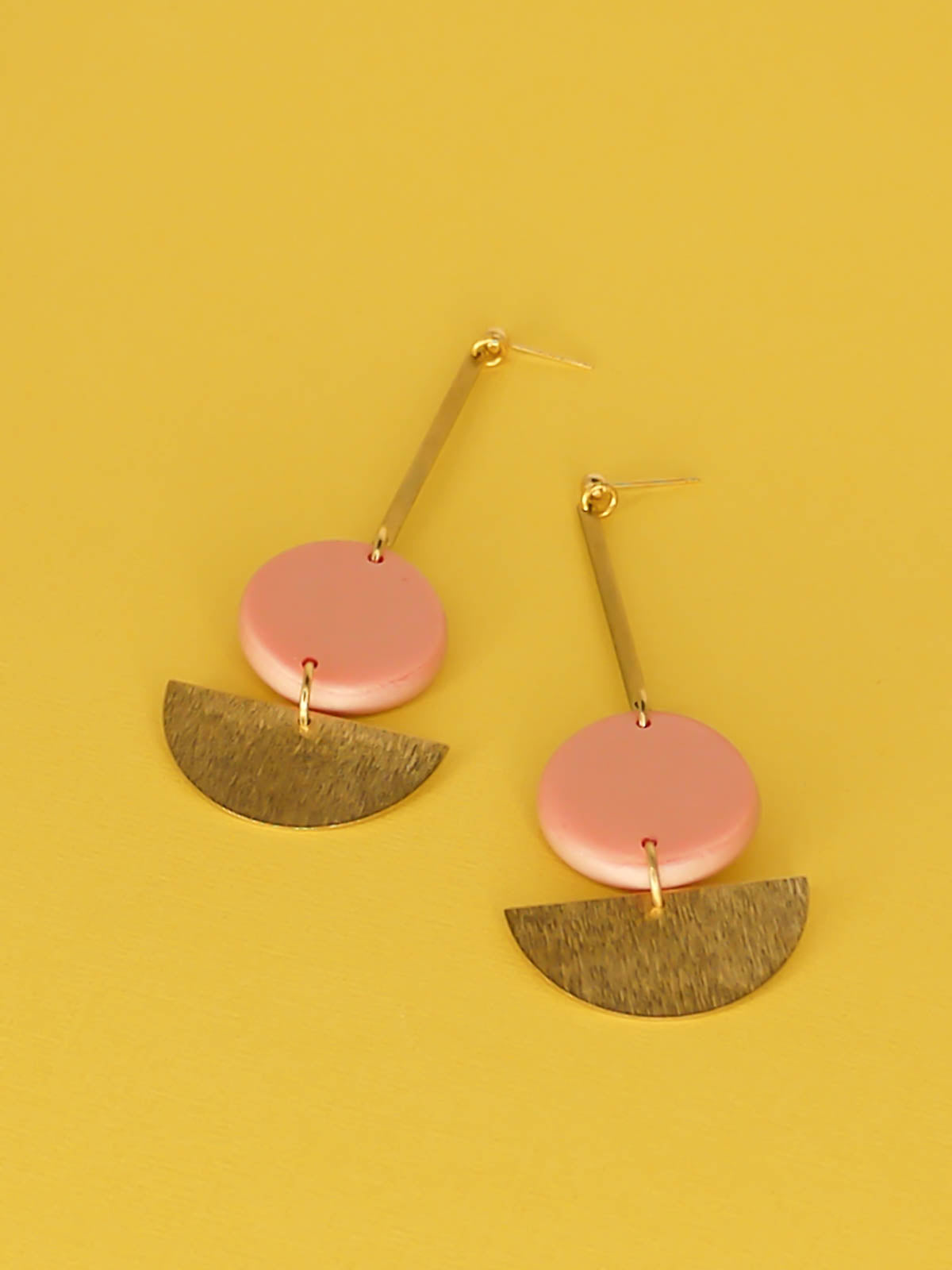 Dangle geometric statement earrings with a gold plated ball stud, a brass stick with a polymer clay round metallic circle in rose gold connected to a textured brass semi circle