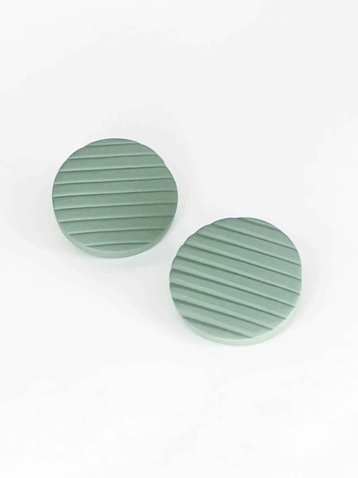 Polymer clay sage green disk stud earrings with a textured stripe and stainless steel posts