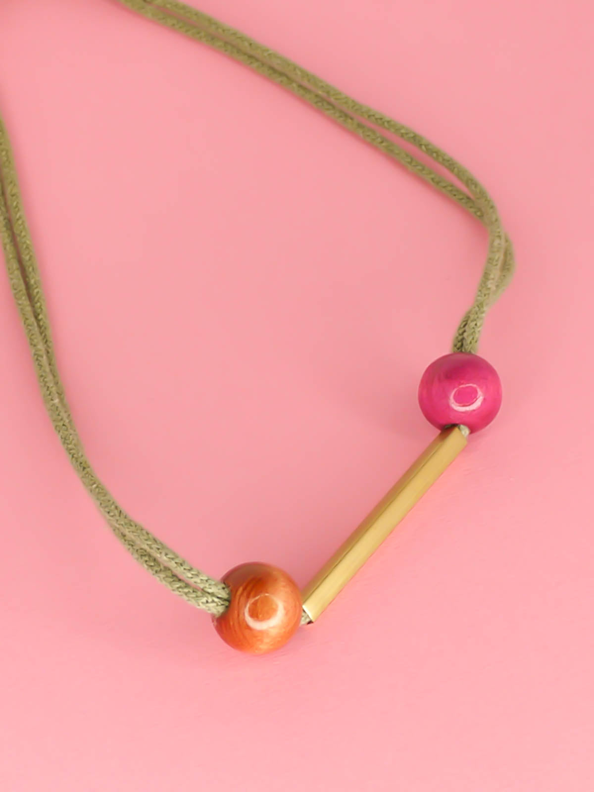 Geometric statement necklace with sage green cotton rope and a brass bar in the centre with wooden beads in pink and brown on either side with a brass bar closure