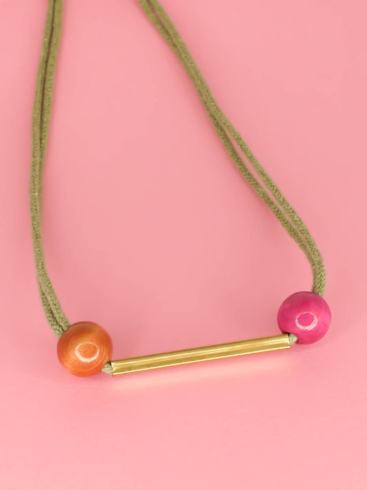 Geometric statement necklace with sage green cotton rope and a brass bar in the centre with wooden beads in pink and brown on either side with a brass bar closure