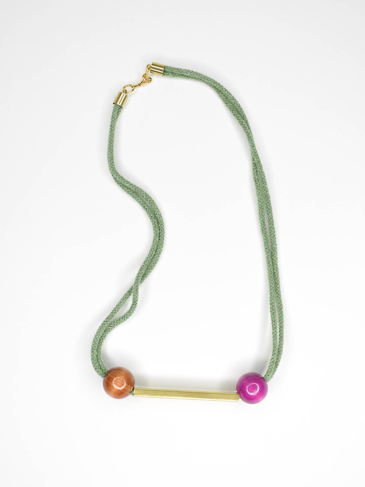 Geometric statement necklace with sage green cotton rope and a brass bar in the centre with wooden beads in pink and brown on either side with a brass bar closure