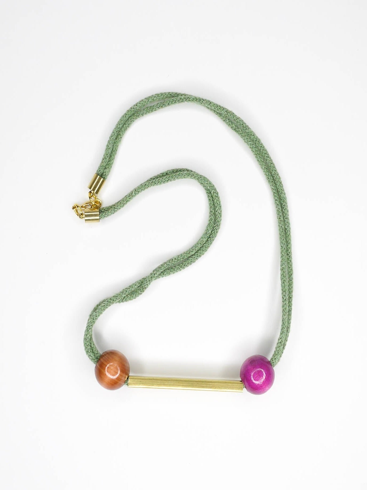 Geometric statement necklace with sage green cotton rope and a brass bar in the centre with wooden beads in pink and brown on either side with a brass bar closure