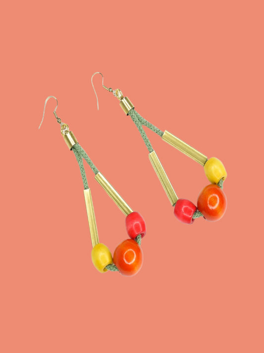 Long bead dangle statement earrings with wooden beads in watermelon, orange & green & brass tube beads strung on mustard coloured cotton rope with brass end caps, hung from gold plated brass earring hooks.