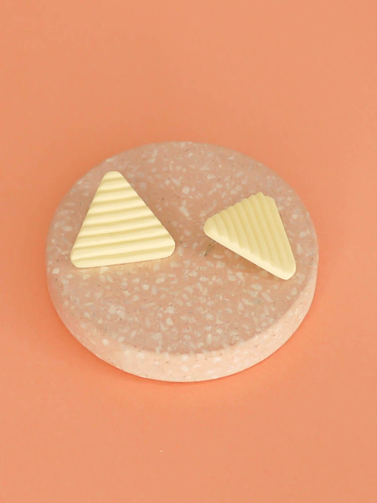 Lightweight yellow polymer clay triangle stud earrings in a fluted striped texture with stainless steel studs.