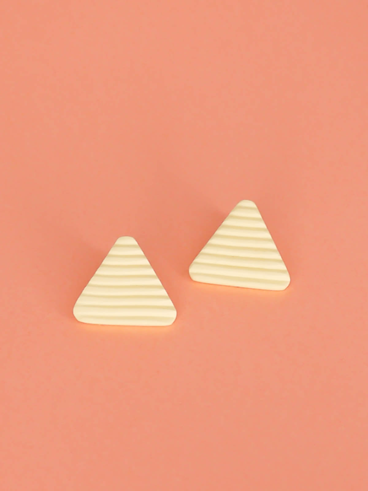 Lightweight yellow polymer clay triangle stud earrings in a fluted striped texture with stainless steel studs.