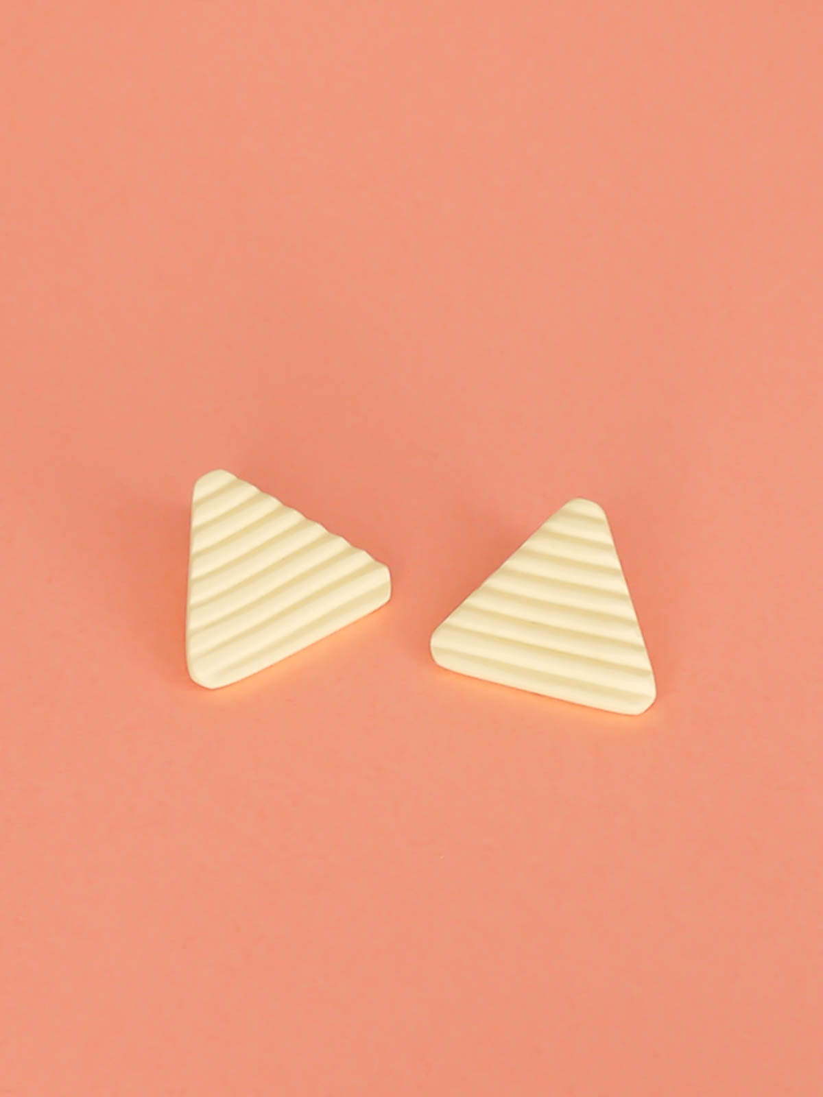 Lightweight yellow polymer clay triangle stud earrings in a fluted striped texture with stainless steel studs.